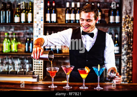 Bartender pouring a orange martini drink in the glass Stock Photo