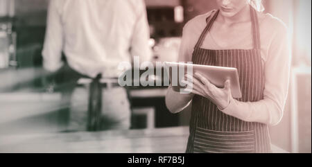 Waitress using digital tablet at counter Stock Photo