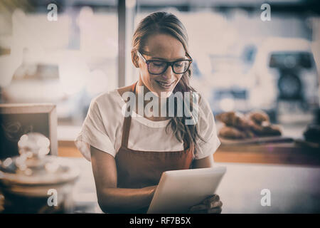 Waitress sitting at table and using digital tablet in cafe Stock Photo