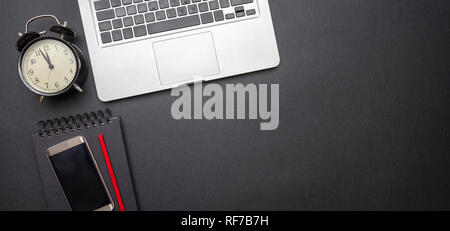 Time management concept. Computer laptop and alarm clock on black color office desk, banner, top view, copy space Stock Photo