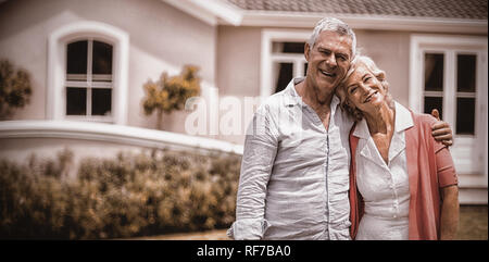 Senior couple with arms around standing in yard Stock Photo