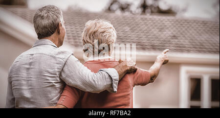 Senior couple looking at house while standing ih yard Stock Photo