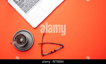 Modern workspace. Computer laptop and mobile phone on orange color office desk, top view, copy space Stock Photo