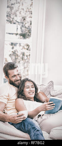 Man holding a cup of coffee while woman reading book Stock Photo