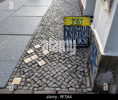 Berlin,Mitte. Street view with Bronze memorial stumbling stones on cobbled pavement outside Book shop Stock Photo