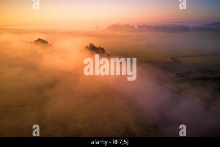 Aerial view of morning foggy river and rural fields. Colorful autumn morning. Sunrise fall scene from above. Minsk region, Belarus. Stock Photo