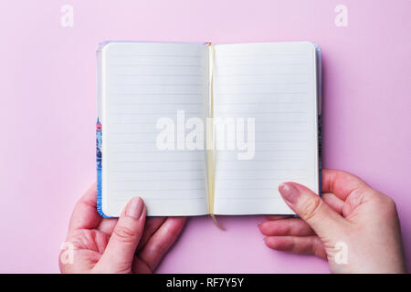 White notebook with clean sheets in the hands of a woman. Pink background. Copy space Stock Photo