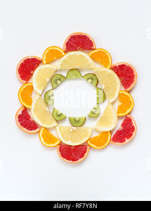 Creative pattern of sliced fruits - kiwi, orange and grapefruits - arranged in a circle. Flat lay with copy space Stock Photo