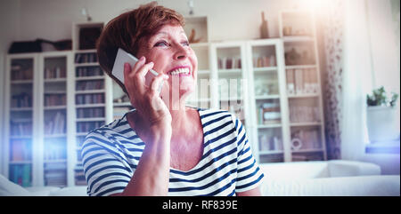 Senior woman talking on mobile phone in living room Stock Photo