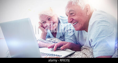 Senior couple using laptop in bedroom Stock Photo