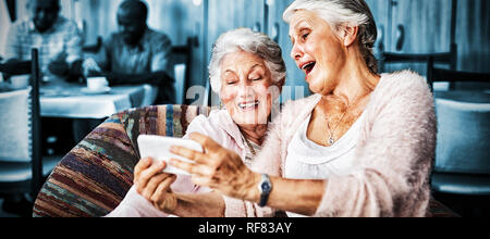 Senior friends taking selfie through smart phone Stock Photo