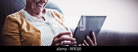 Smiling senior woman looking and laughing at her digital tablet Stock Photo