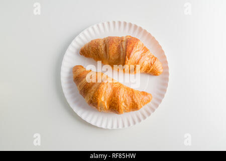 Two plain croissant on the plate, white table background Stock Photo