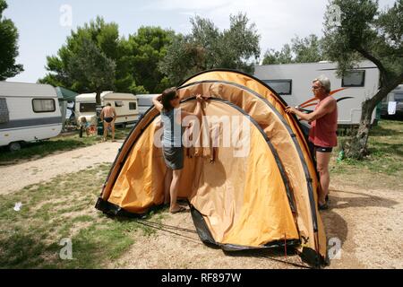 Setting up a tent at Kovacine Campground, with its concrete beach, swimming, and boat docks, Cres Island, Croatia, Europe Stock Photo