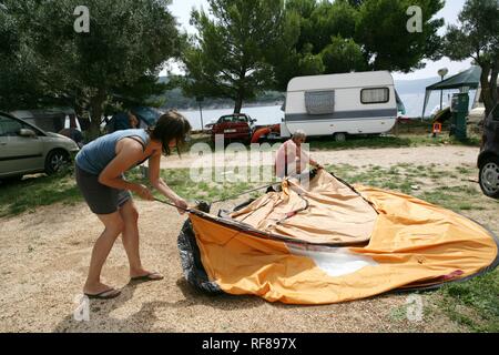 Setting up a tent at Kovacine Campground, with its concrete beach, swimming, and boat docks, Cres Island, Croatia, Europe Stock Photo