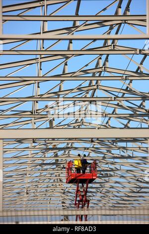 Workers on an aerial work platform (lift platform) during construction of a warehouse in Duisburg, North Rhine-Westphalia Stock Photo