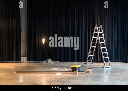 Construction in factory building or warehouse interior. Ladder, repairing tools, wires in concrete floor Stock Photo