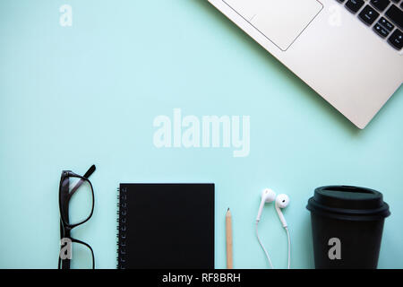 Workspace in a trendy blue color. Many different things including a laptop and headphones are on the table. Stock Photo