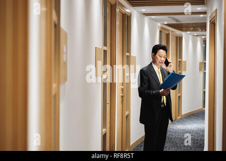 Asian Manager Working As Banking Agent Talking On Cell Phone Stock Photo