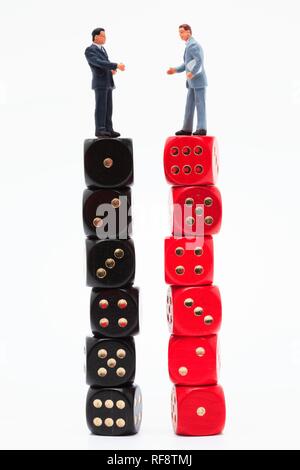 Small men standing on large stacks of dice: symbol for success Stock Photo
