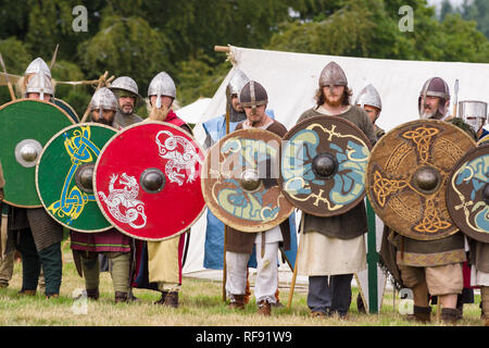 Medieval re-enactors dressed in armour and costumes of the 12th century equipped with weapons re-enacting combat of the period Stock Photo