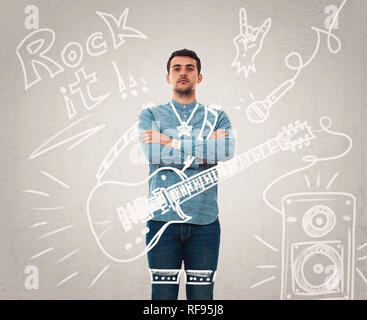 Confident young man arms crossed imagine him as a musician with a guitar performing on stage. Dream come true as sketches on the background. Rock star Stock Photo