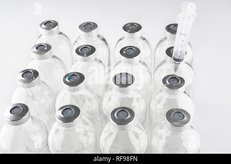 Used medical phials with metal caps. Syringe stuck into bottle. Stock Photo