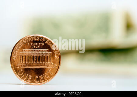 Close up of one cent coin with American dollar notes on the background Stock Photo
