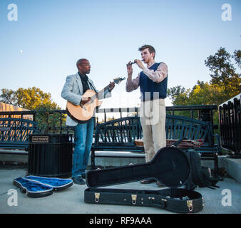 Two musicians, a guitarist and flute player, busk on a bridge in Old Town Lansing, Michigan, during Bluesfest Stock Photo