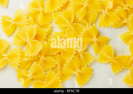 Dry Italian pasta called farfalle on a white tablecloth background , beautiful bow tie shape pasta Stock Photo