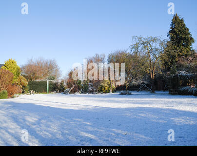 A crisp winter morning shot of the garden showing snow on wide expanse of lawn in a UK garden Stock Photo