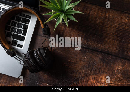 Laptop, headphones, pens and plant on old wooden table Stock Photo