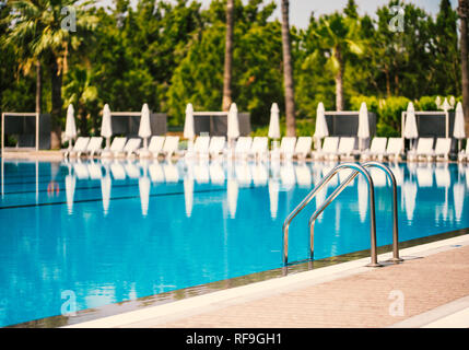 Grab bars ladder in the blue swimming pool Stock Photo