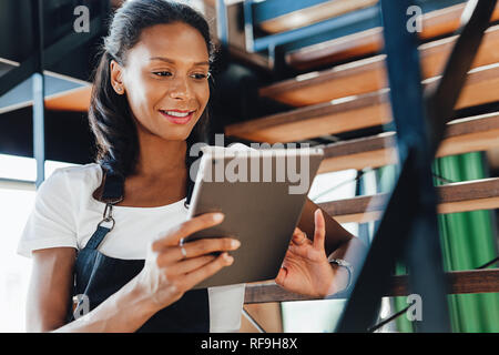 Young coffee shop owner using a digital tablet while sitting on a stairs Stock Photo