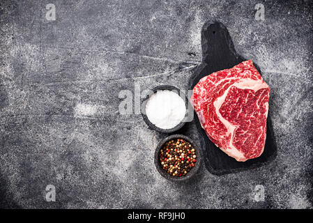 Raw marbled ribeye steak and spices Stock Photo
