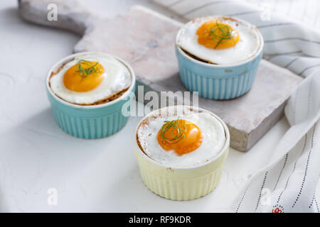 Three baked egg in ramekins on white background Stock Photo