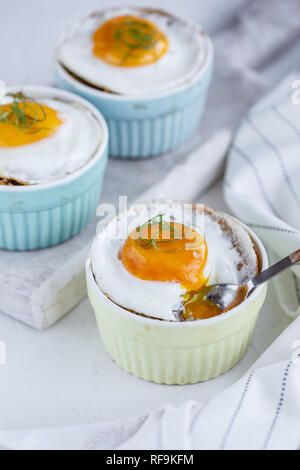 Three baked egg in ramekins on white background Stock Photo
