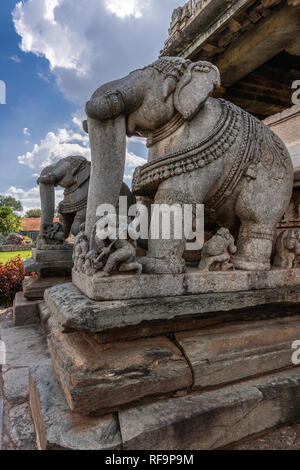 Belavadi, Karnataka, India - November 2, 2013: Veera Narayana Temple. Closeup of two gray stone large statues of elephant on steps to sanctuary. Red r Stock Photo