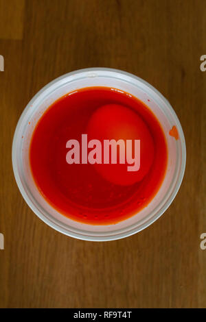 Egg in a plastic cup to get coloured in red for easter Stock Photo