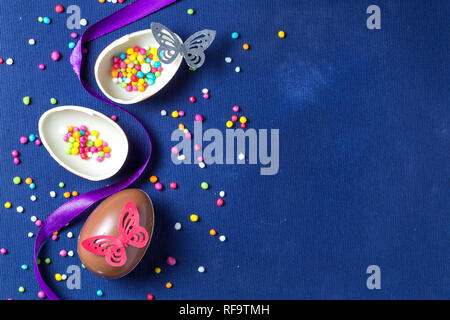 Chocolate Easter eggs with many color sweet over blue background. Easter composition with chocolate eggs and space for text.. Stock Photo