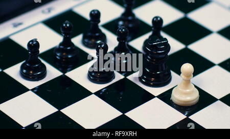 white chess pieces lined up against all black pawns, ideal footage to represent problems of integration, violence and racism Stock Photo