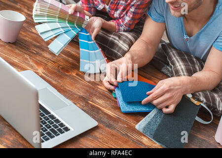 Young couple moving to new place lying using laptop choosing color and flooring close-up happy Stock Photo