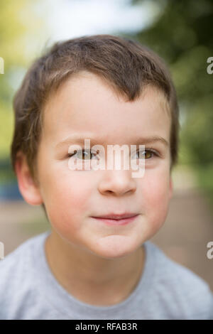 Closeup portrait of a smiling freckled boy with dark hair and brown eyes outdoors Stock Photo