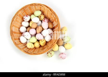 Chocolate mini Easter eggs in straw or whicker basket against a white background Stock Photo