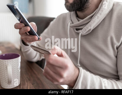 close-up of man entering credit card information while shopping on the internet on smartphone Stock Photo