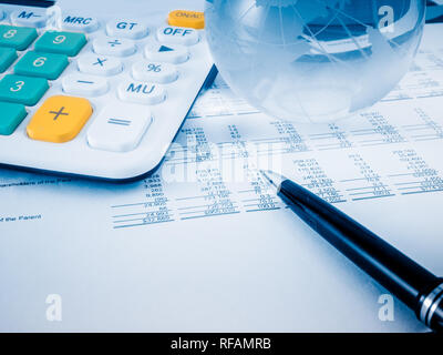 A close-up shot of a calculator. A printed balance sheet and a pen are ...