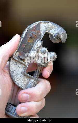 Hand holding pipe cutting tool used to cut copper pipe and tubing Stock Photo