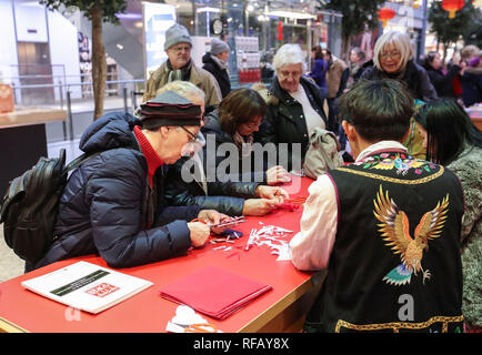 Berlin, Germany. 24th Jan, 2019. Visitors learn traditional Chinese paper cutting in a shopping mall at Potsdamer Platz in Berlin, capital of Germany, on Jan. 24, 2019. 'Happy Chinese New Year,' a series of Chinese cultural celebrations for the upcoming Spring Festival, kicked off in downtown Berlin on Thursday. Credit: Shan Yuqi/Xinhua/Alamy Live News Stock Photo