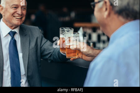 Senior business people toasting beer glasses at bar after work. business professionals having drinks after work at the bar. Stock Photo