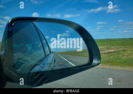 Blue cloudy sky landscape sunset reflect in mirror of car during the car moving. You can see a photographer with camera on mirror. Stock Photo
